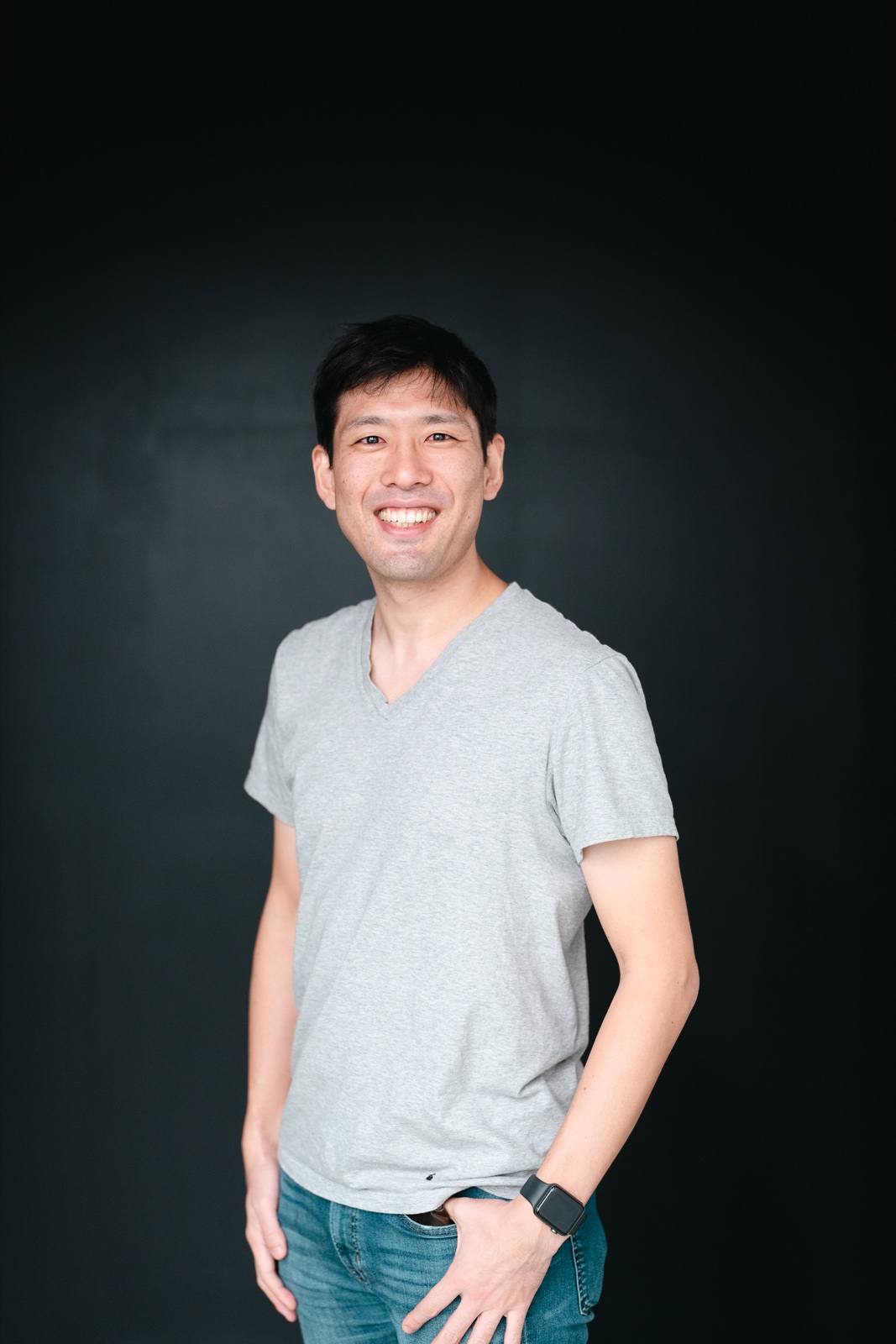 Yusuke Urakami smiling against a dark background